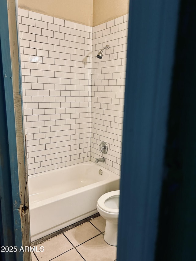 bathroom featuring tiled shower / bath combo, tile patterned floors, and toilet