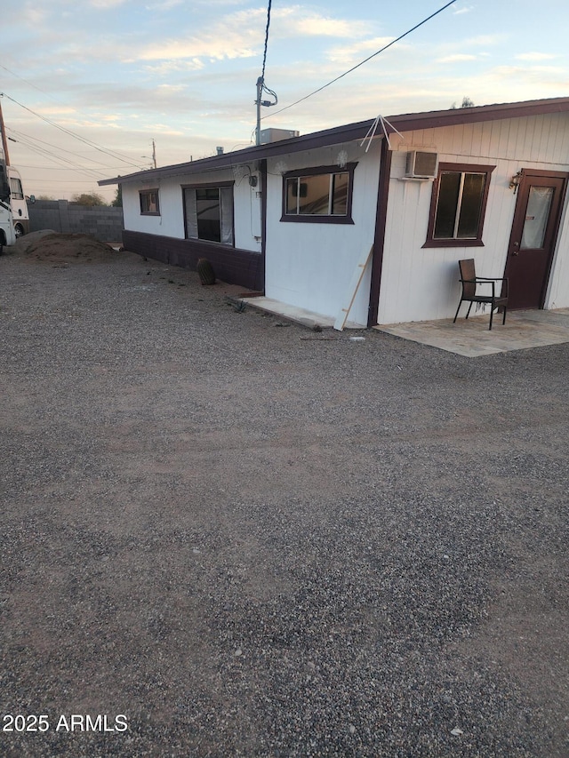 view of front of house with a patio and a wall mounted AC