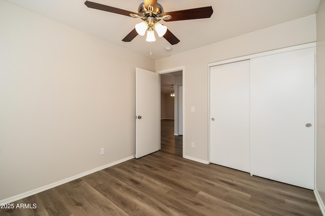 unfurnished bedroom with a closet, wood finished floors, a ceiling fan, and baseboards