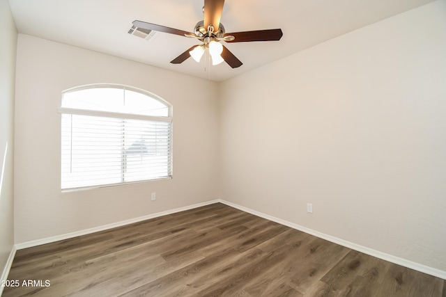 empty room featuring visible vents, dark wood finished floors, baseboards, and ceiling fan