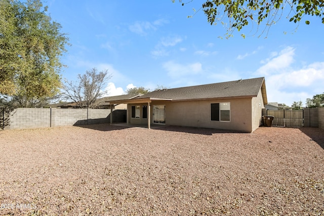 back of house featuring a patio area, a fenced backyard, a gate, and stucco siding