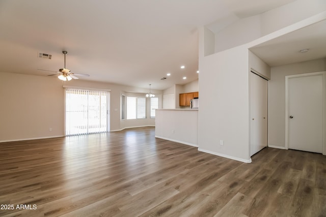 unfurnished living room with baseboards, visible vents, wood finished floors, vaulted ceiling, and ceiling fan with notable chandelier