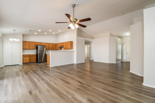 unfurnished living room featuring visible vents, baseboards, wood finished floors, and ceiling fan with notable chandelier