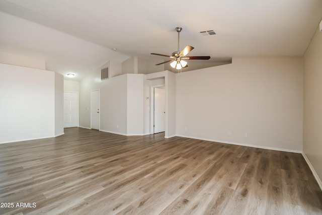 unfurnished room with visible vents, vaulted ceiling, and wood finished floors