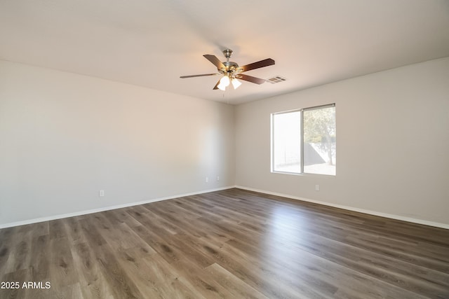 spare room with ceiling fan, wood finished floors, visible vents, and baseboards