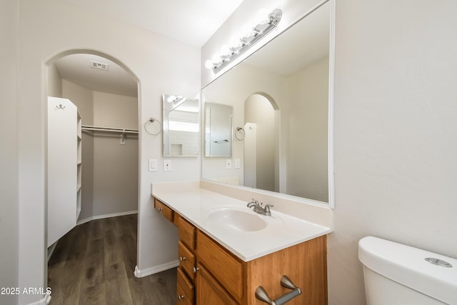 bathroom featuring visible vents, toilet, vanity, wood finished floors, and baseboards