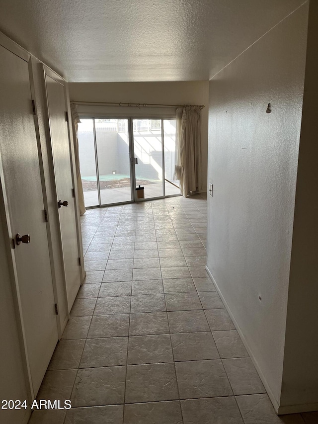 corridor featuring light tile patterned floors and a textured ceiling