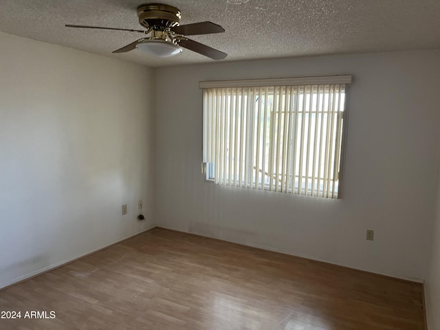 unfurnished room with ceiling fan, a textured ceiling, and light wood-type flooring