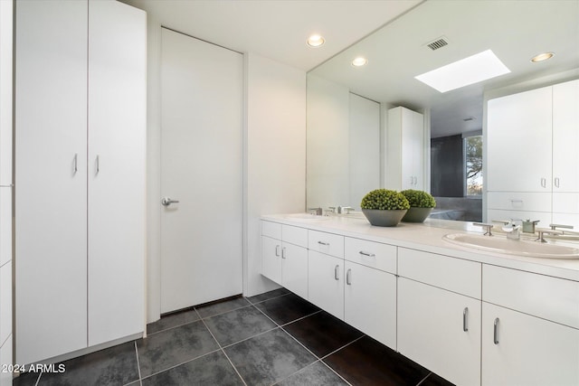 bathroom with tile patterned floors, vanity, and a skylight