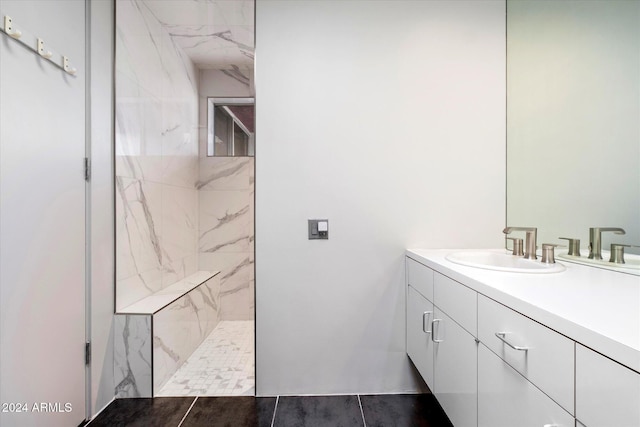 bathroom with tile patterned flooring, vanity, and tiled shower