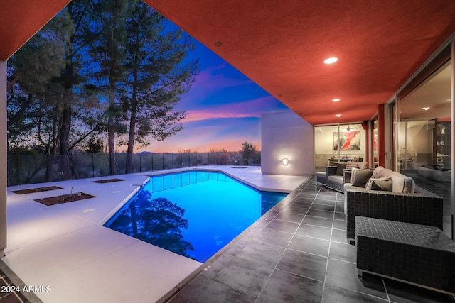 pool at dusk with a patio area and an outdoor living space