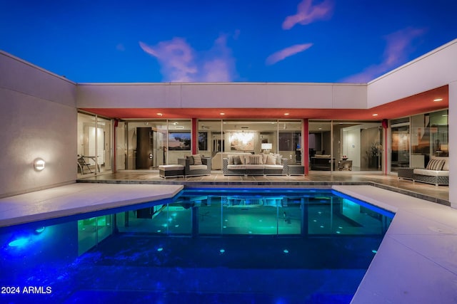 pool at dusk with an outdoor living space and a patio