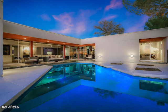 pool at dusk featuring an outdoor living space and a patio area