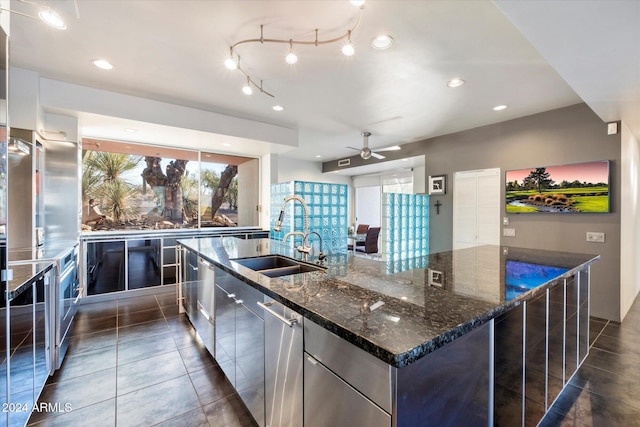 kitchen featuring dark stone counters, sink, stainless steel dishwasher, ceiling fan, and a large island