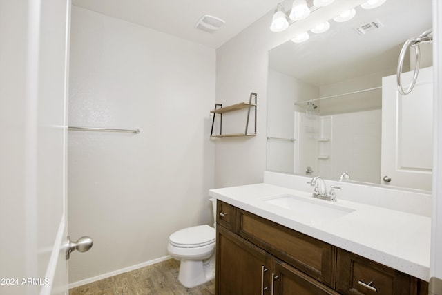 bathroom featuring vanity, hardwood / wood-style flooring, toilet, and a shower