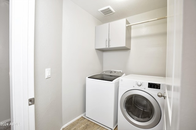 clothes washing area featuring cabinets, light hardwood / wood-style floors, and independent washer and dryer