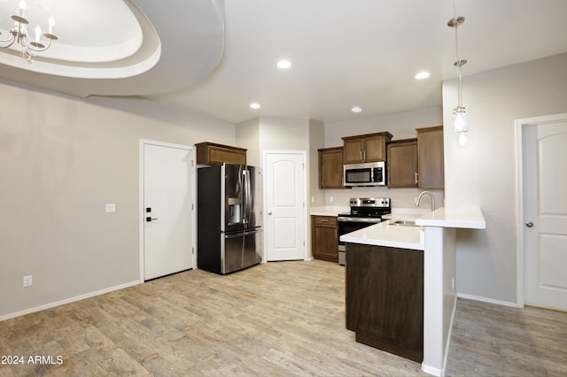 kitchen with sink, decorative light fixtures, appliances with stainless steel finishes, and light hardwood / wood-style flooring