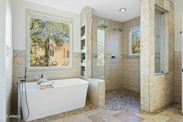 full bath with a soaking tub, walk in shower, a wealth of natural light, and tile walls