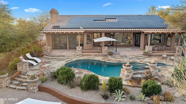 back of property with an outdoor pool, a patio, a chimney, a tiled roof, and outdoor dining space