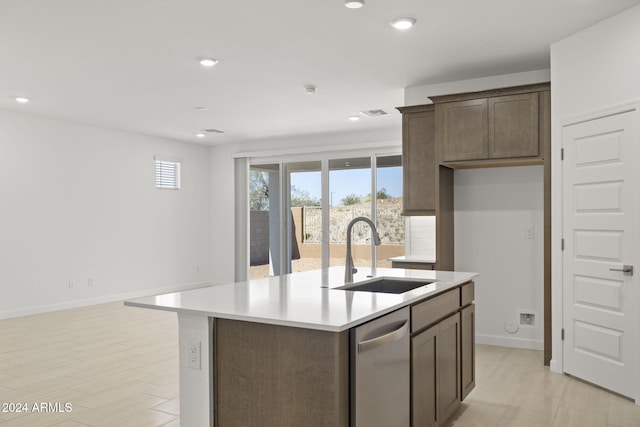 kitchen with dark brown cabinetry, sink, an island with sink, and stainless steel dishwasher