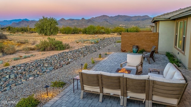 patio terrace at dusk featuring a mountain view and an outdoor living space with a fire pit