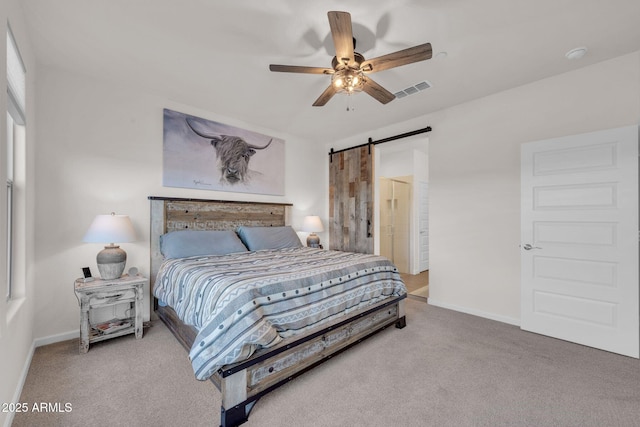 carpeted bedroom featuring a barn door and ceiling fan