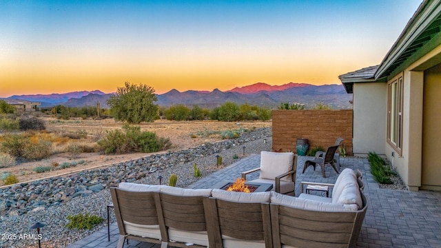 patio terrace at dusk with a mountain view and an outdoor living space with a fire pit