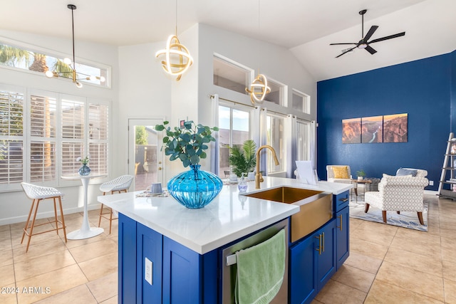 kitchen with blue cabinets, a kitchen island with sink, sink, and hanging light fixtures