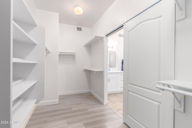 walk in closet with light hardwood / wood-style floors