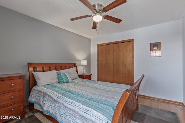 bedroom featuring a closet, wood finished floors, baseboards, and ceiling fan