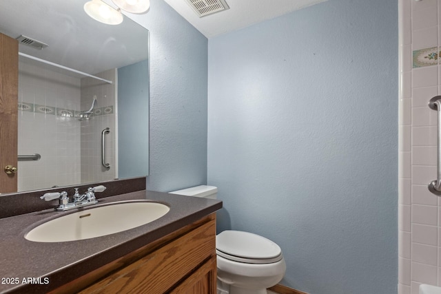 bathroom with toilet, a shower, vanity, and a textured wall