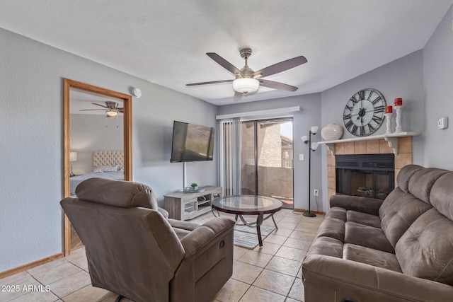 living area with light tile patterned flooring, ceiling fan, and baseboards