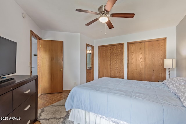 bedroom with two closets, wood finished floors, and ceiling fan