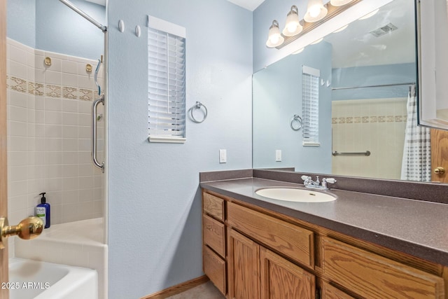 full bathroom featuring tiled shower and vanity