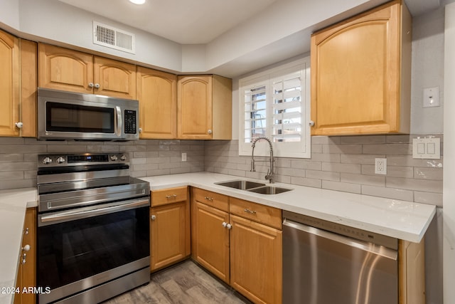 kitchen featuring light wood-type flooring, appliances with stainless steel finishes, sink, and tasteful backsplash