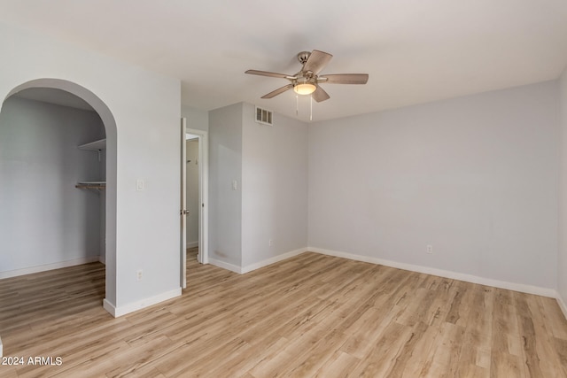 unfurnished bedroom featuring ceiling fan, a closet, light hardwood / wood-style floors, and a spacious closet