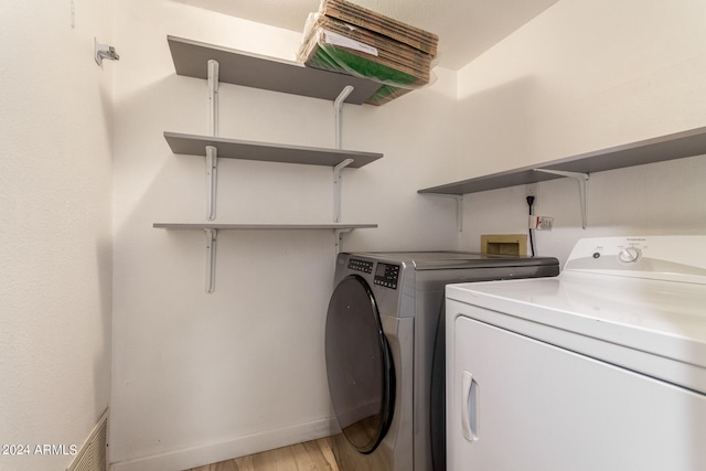 clothes washing area featuring separate washer and dryer and light wood-type flooring