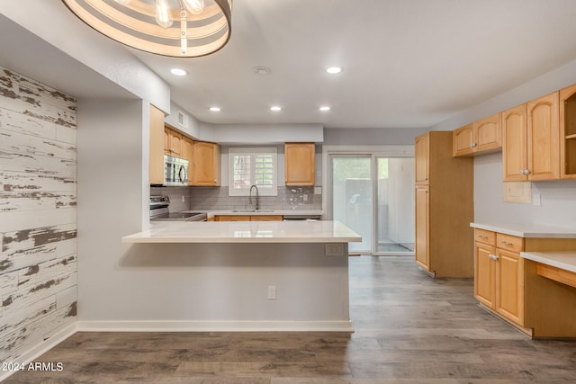 kitchen featuring sink, kitchen peninsula, appliances with stainless steel finishes, and hardwood / wood-style floors