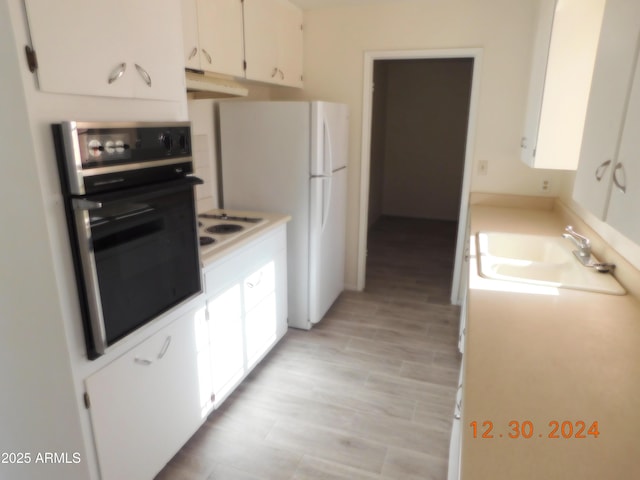 kitchen with sink, white stovetop, black oven, white cabinets, and light wood-type flooring