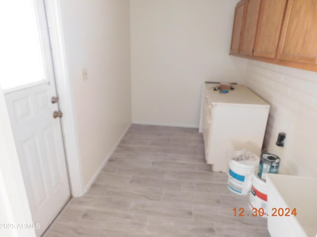 clothes washing area with light hardwood / wood-style floors