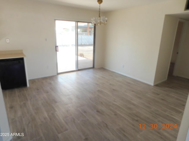 unfurnished living room with wood-type flooring and an inviting chandelier