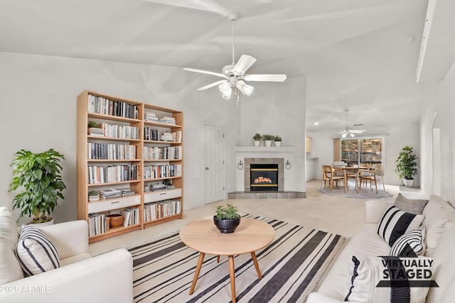 living room with carpet floors, ceiling fan, lofted ceiling, and a tiled fireplace