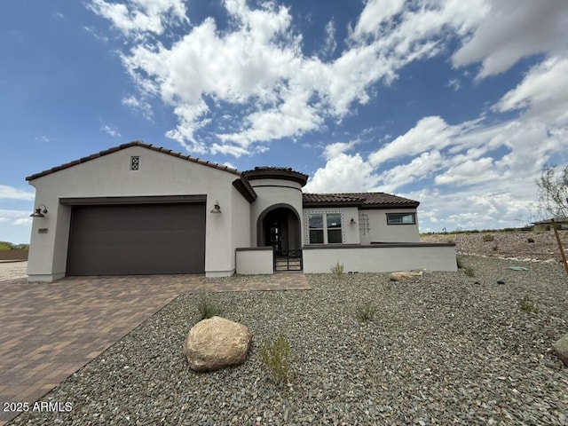 4448 Bucking Bronco Rd, Wickenburg, AZ 85390 - mediterranean / spanish-style house with stucco siding, an attached garage, a tiled roof, and decorative driveway