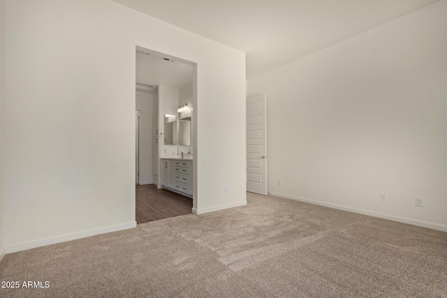 unfurnished bedroom featuring carpet floors, a sink, ensuite bath, and baseboards