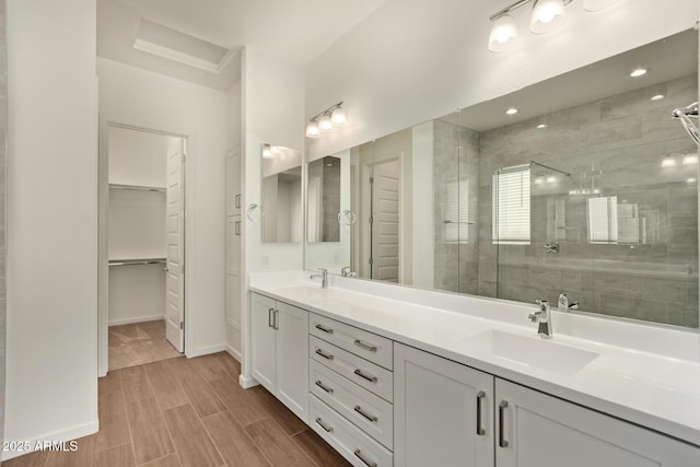 full bath with a sink, double vanity, a stall shower, and a walk in closet