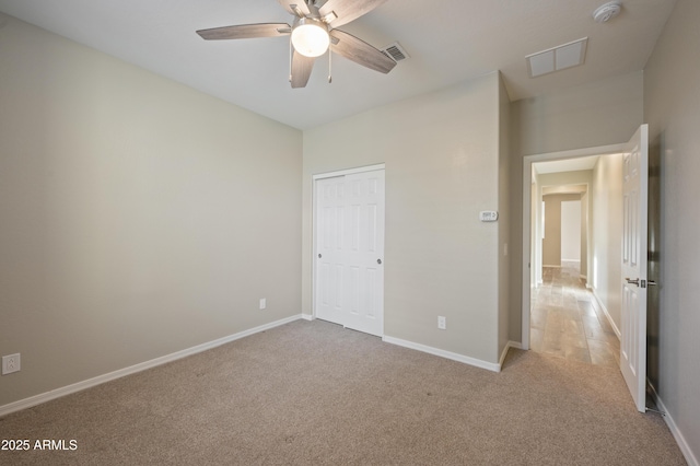 unfurnished bedroom with ceiling fan, light colored carpet, and a closet