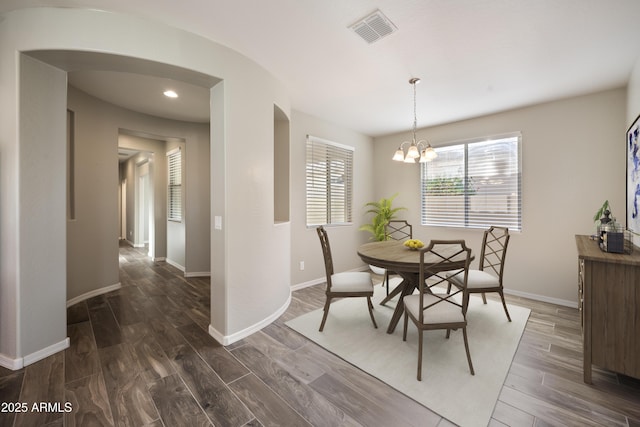 dining space featuring dark wood-type flooring and an inviting chandelier