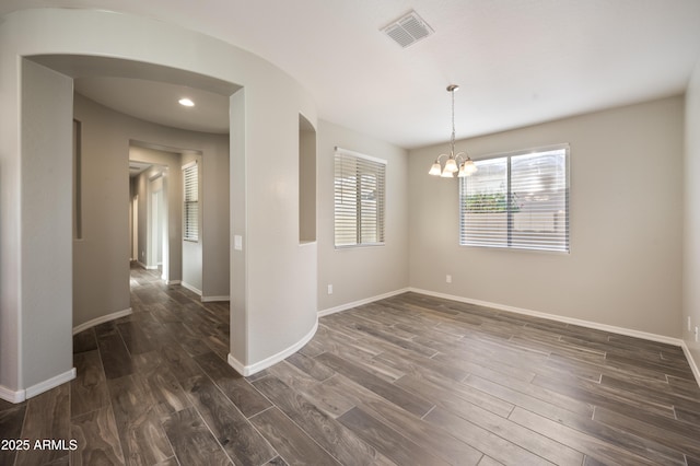 empty room featuring dark hardwood / wood-style flooring and a notable chandelier