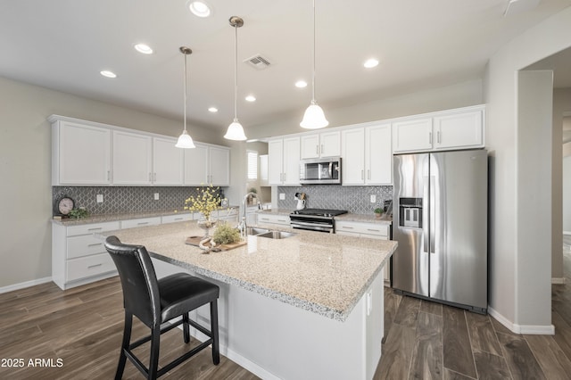 kitchen with white cabinetry, stainless steel appliances, sink, and pendant lighting