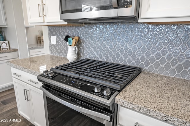 kitchen with light stone counters, dark hardwood / wood-style floors, stainless steel appliances, decorative backsplash, and white cabinets